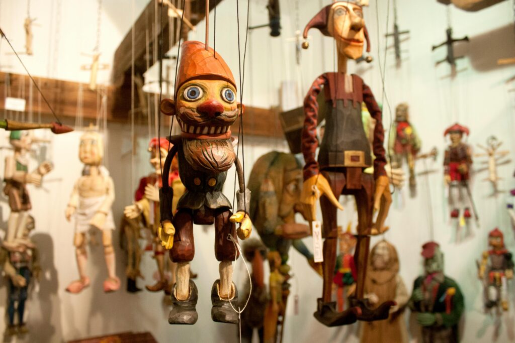 Close-up of intricately crafted wooden marionettes on display with strings attached.